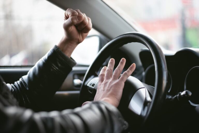 man honking horn with a raised fist while driving in Alabama traffic.