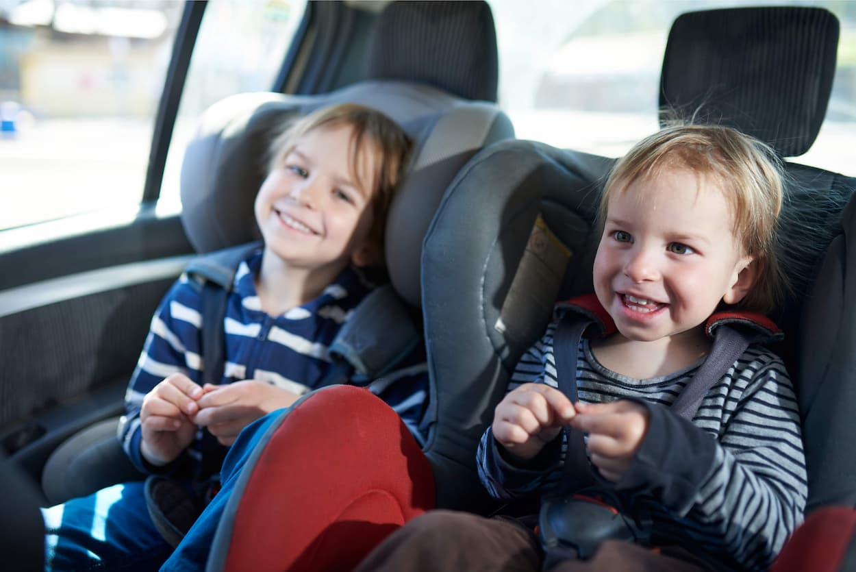 two kids laughing in their car seats