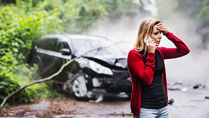 woman using cellphone to call insurance after a car accident