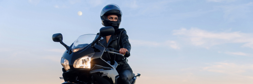 driver in a motorcycle wearing his helmet and heading onto the sunset