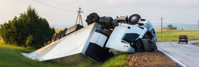 semi truck turned over on the side of the road after a collision