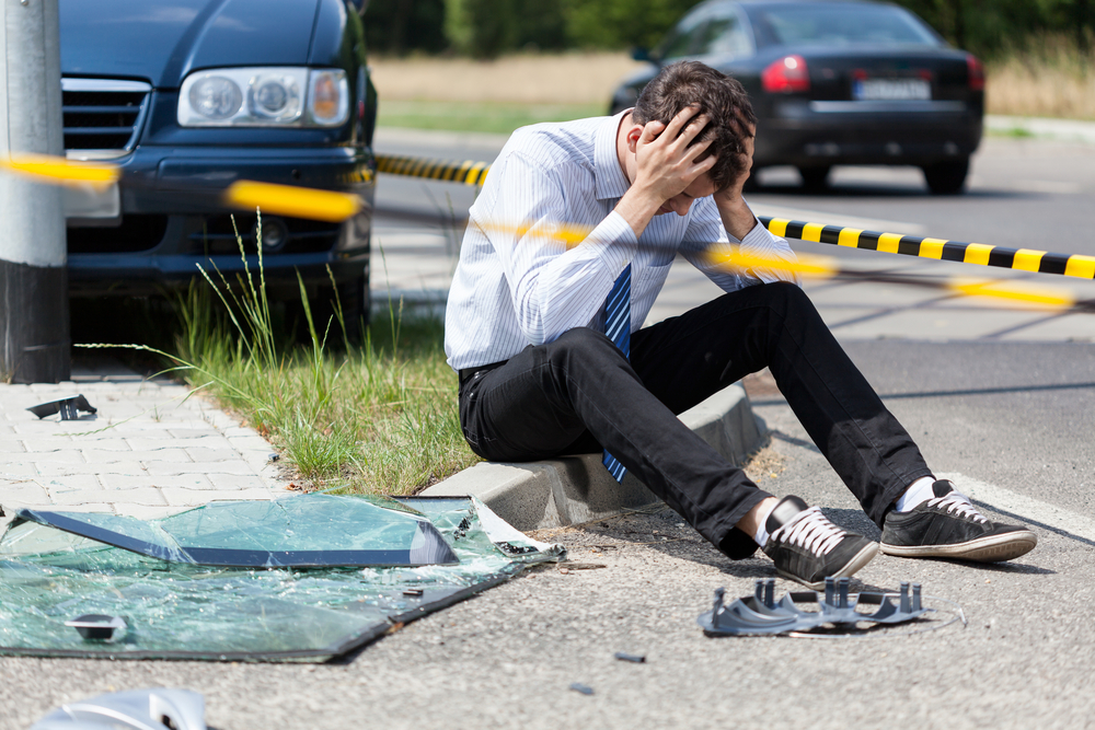 man holding his head, shocked, at a crash scene
