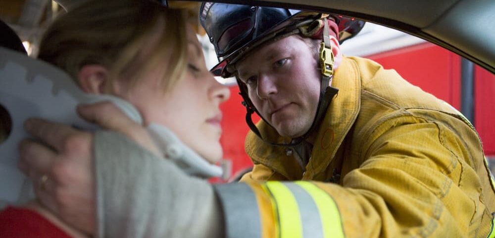 firefighter helping injured women out of a car with neck brae