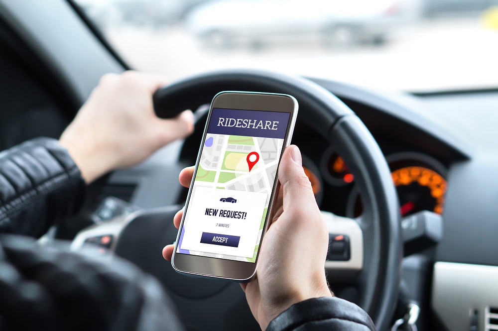 driver holding a mobile phone with a rideshare app