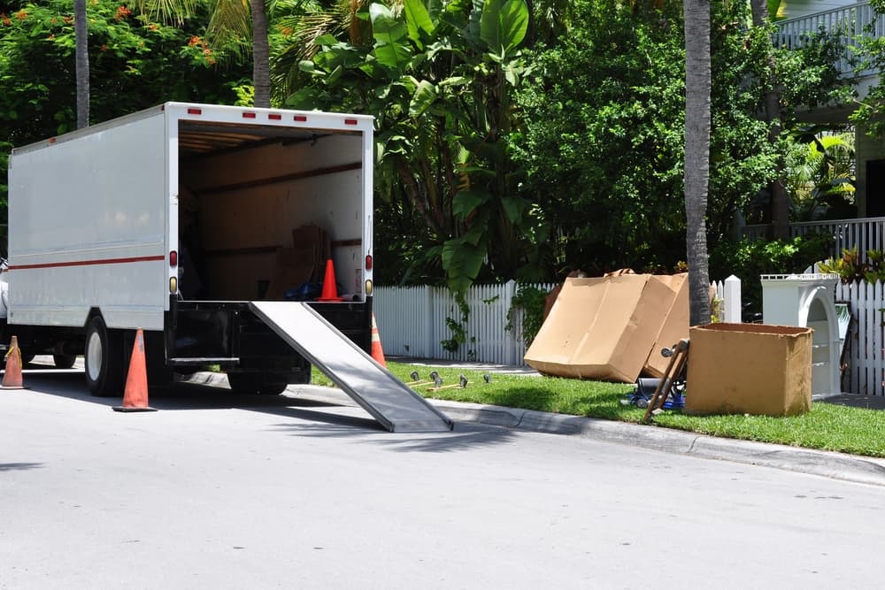 moving van parked at curb where boxes sit