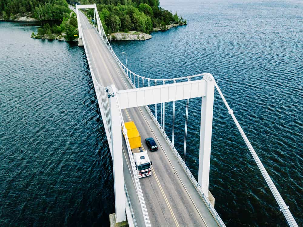 birdeye view of commercial truck driving over a bridge suspended above water