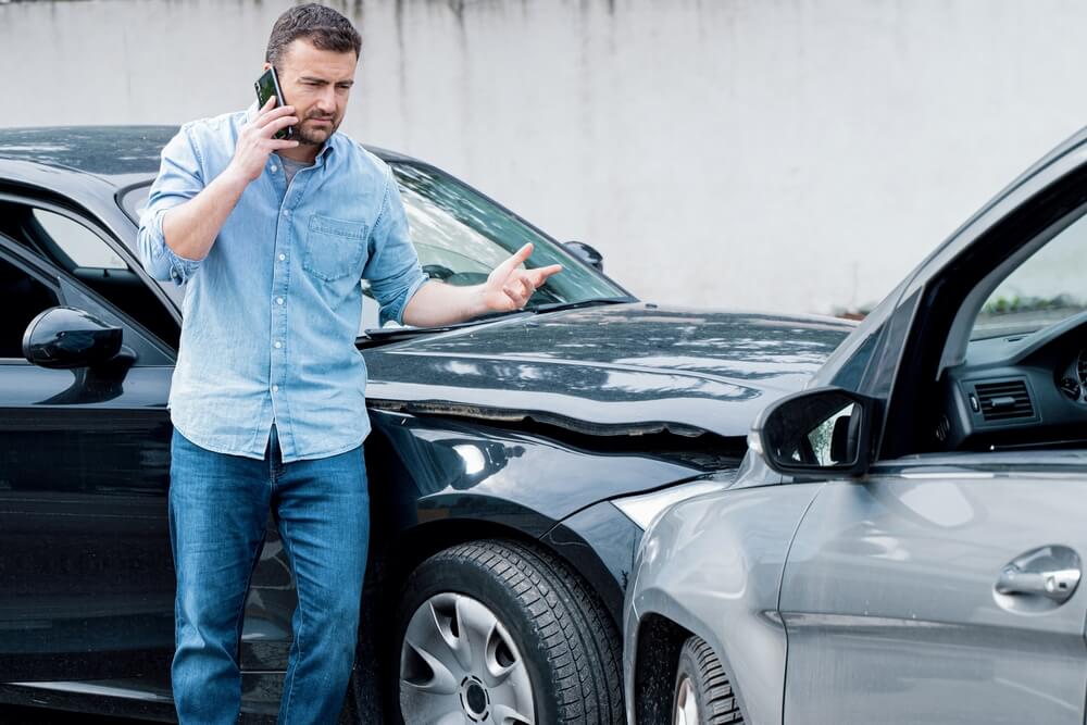 One man reporting car crash damage calling insurance roadside service
