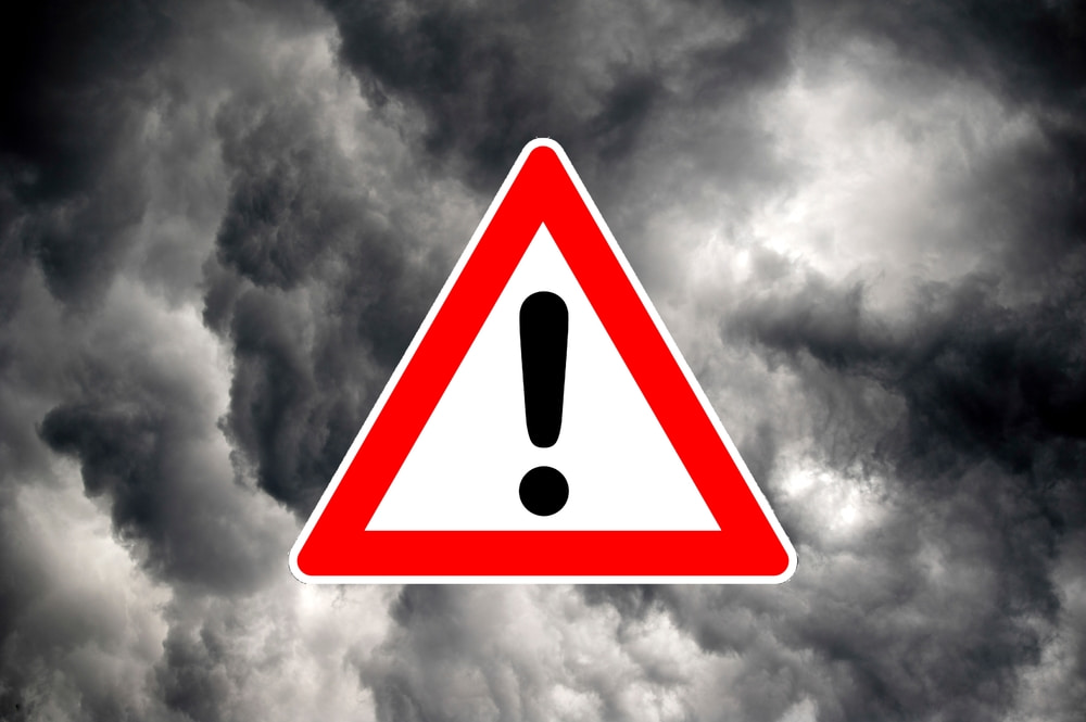 warning sign laid over background of dark stormy sky