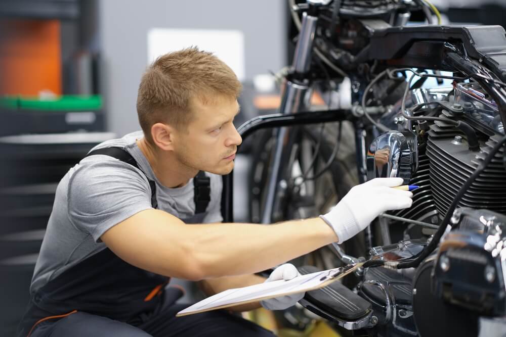 A man in the garage is checking a motorcycle