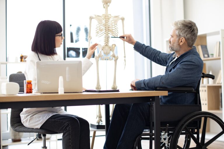 a man and woman looking at a spinal cord on a fake skeleton
