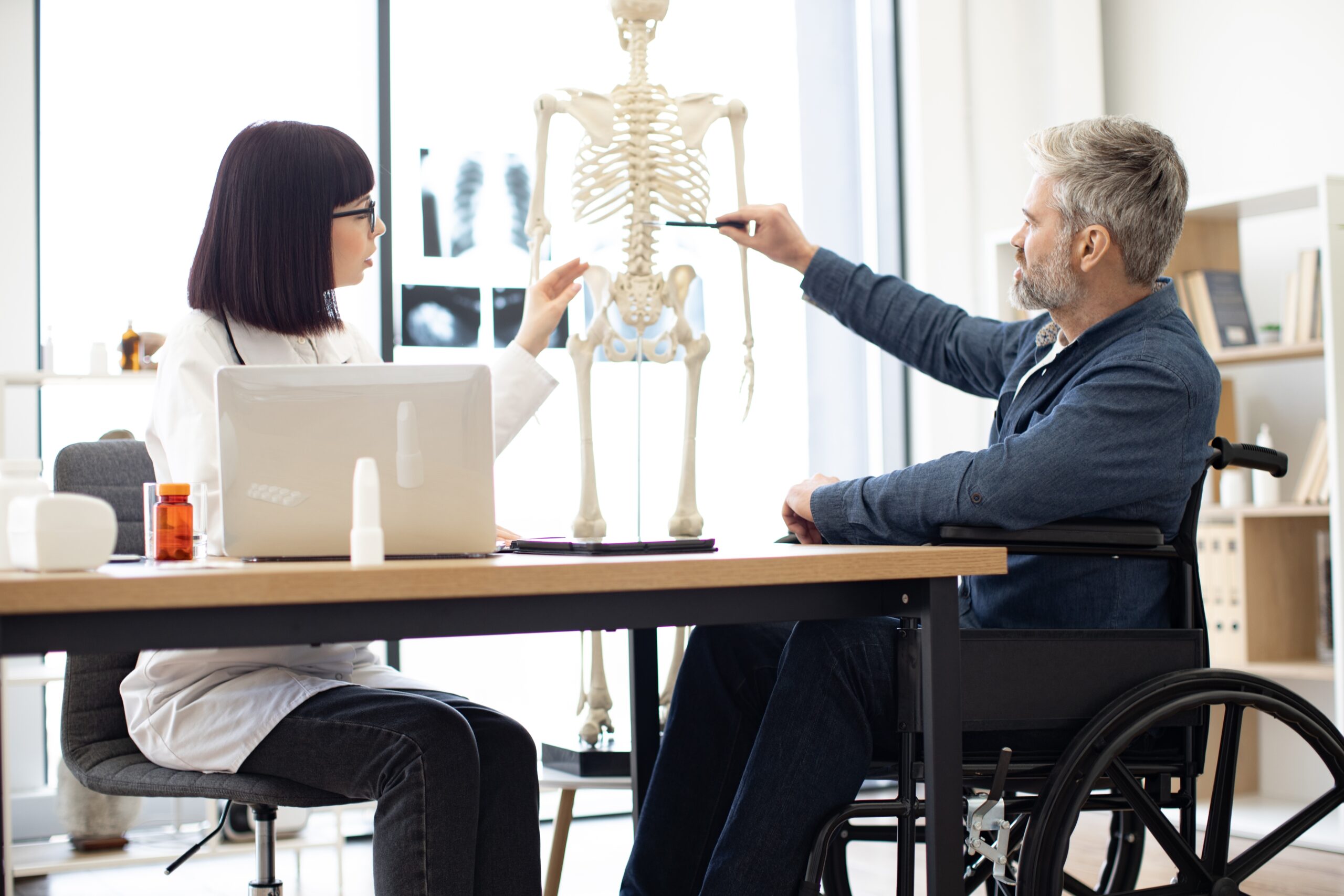 a man and woman looking at a spinal cord on a fake skeleton
