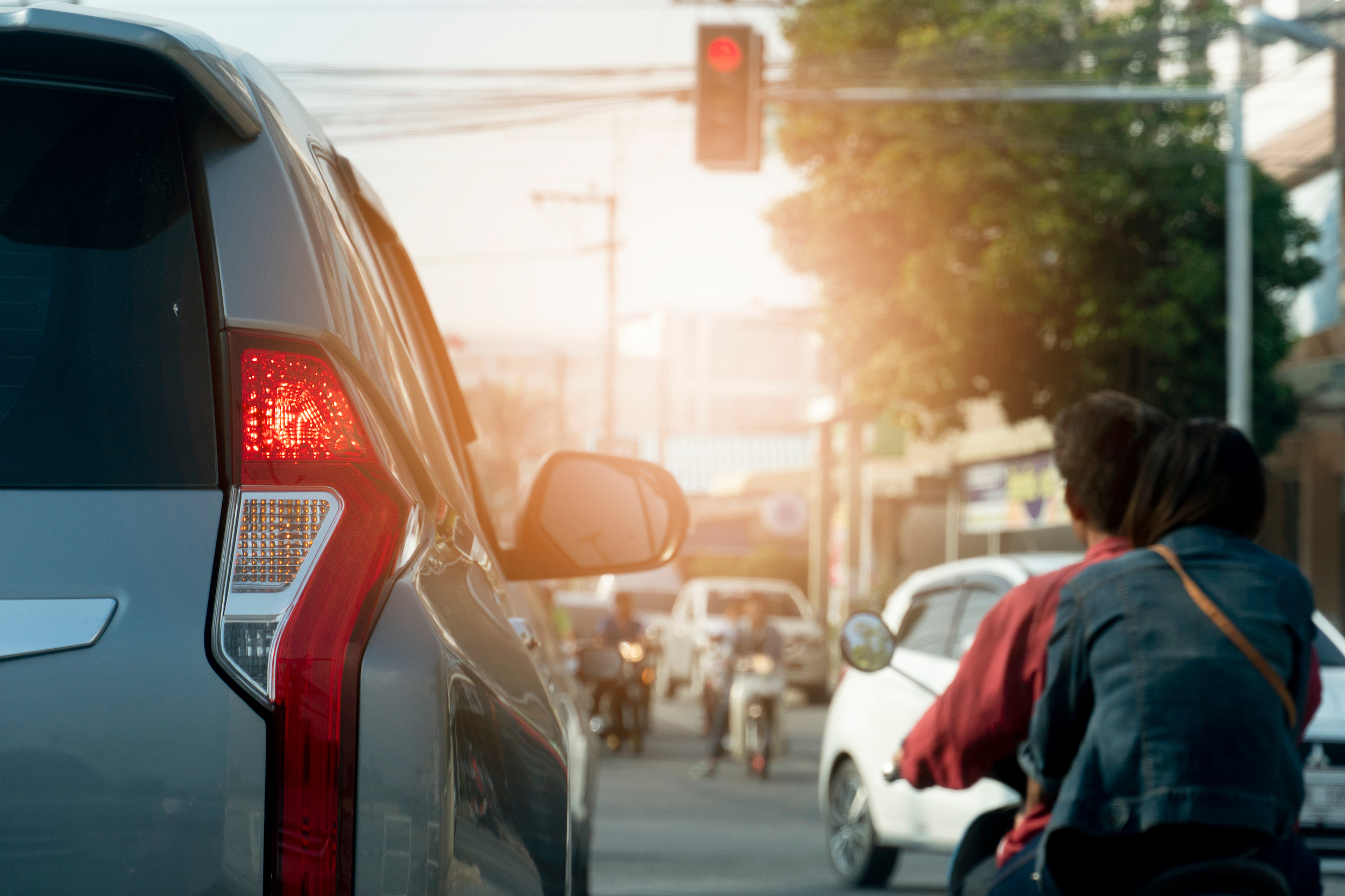 car at a red light with bicyclists to the right of it