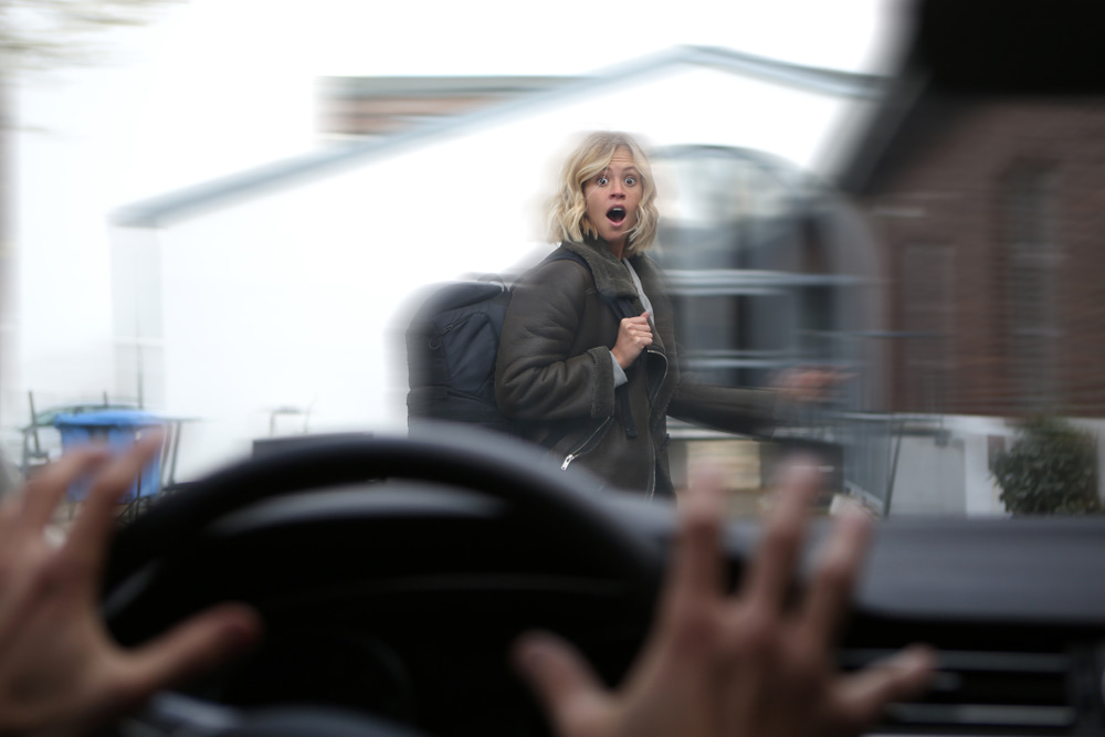 woman crossing street in front of a car, point of view being the driver