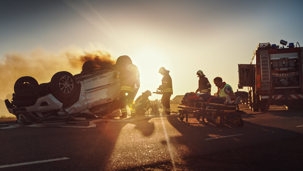 paramedics responding to a car accident where car is flipped upside down on road