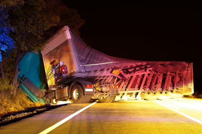 A truck is flipped over on the roadside, illustrating a fatal truck accident and the need for legal support.