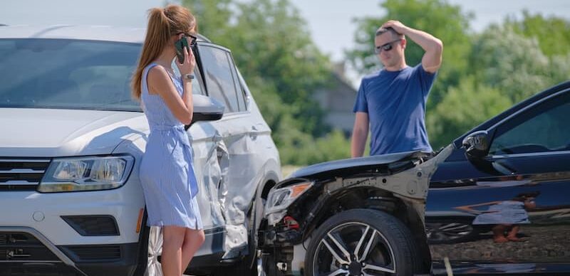 A woman speaks on her cell phone beside a damaged car after a T-bone accident in Huntsville.