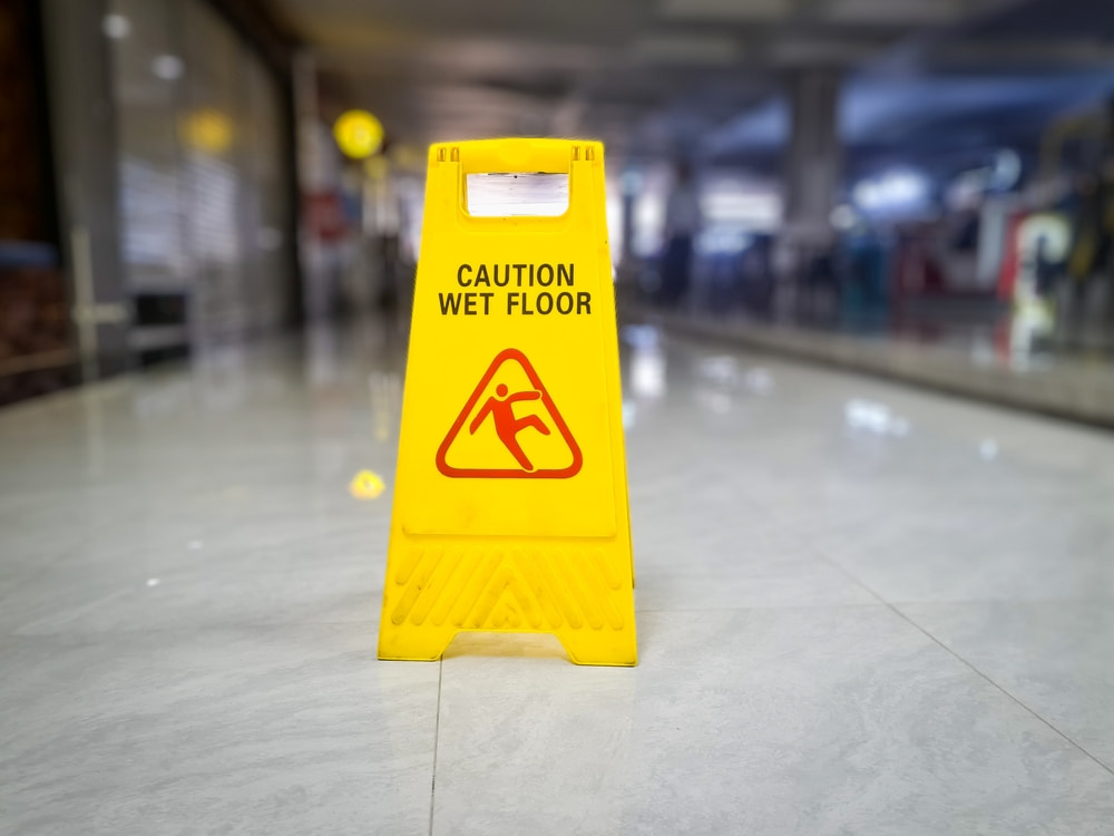 Caution Wet Floor sign laid on light colored flooring in shopping mall