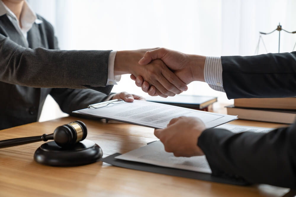 Lawyers shake hands with business people to seal a deal with partner lawyers.