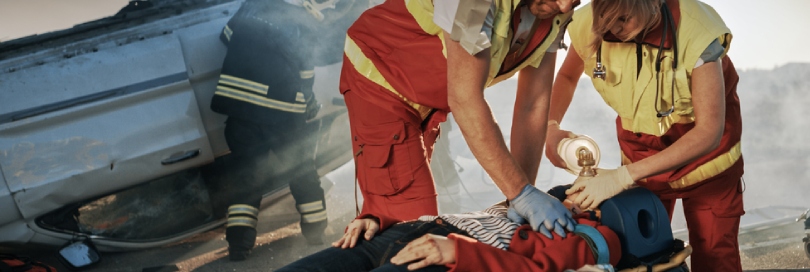 Woman on a stretcher being assisted by paramedics after a car accident