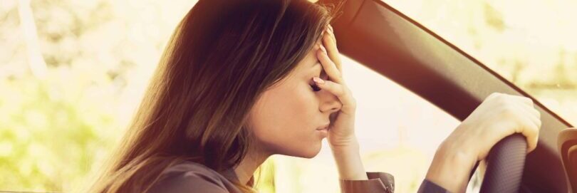 female driver stressed out; holding hand to face