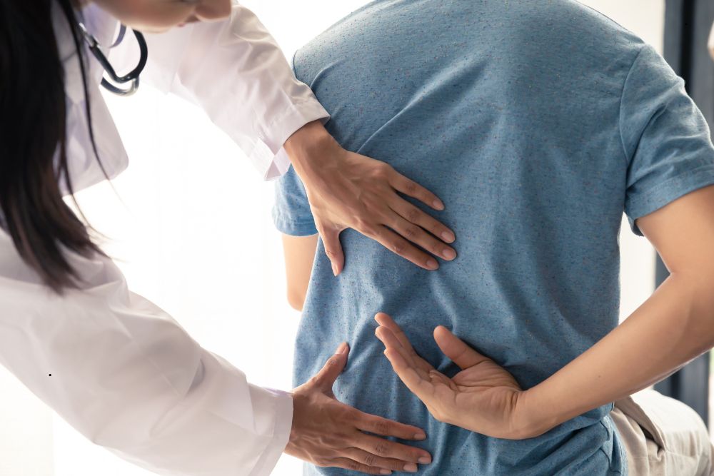 Doctor examining a male patient with back pain